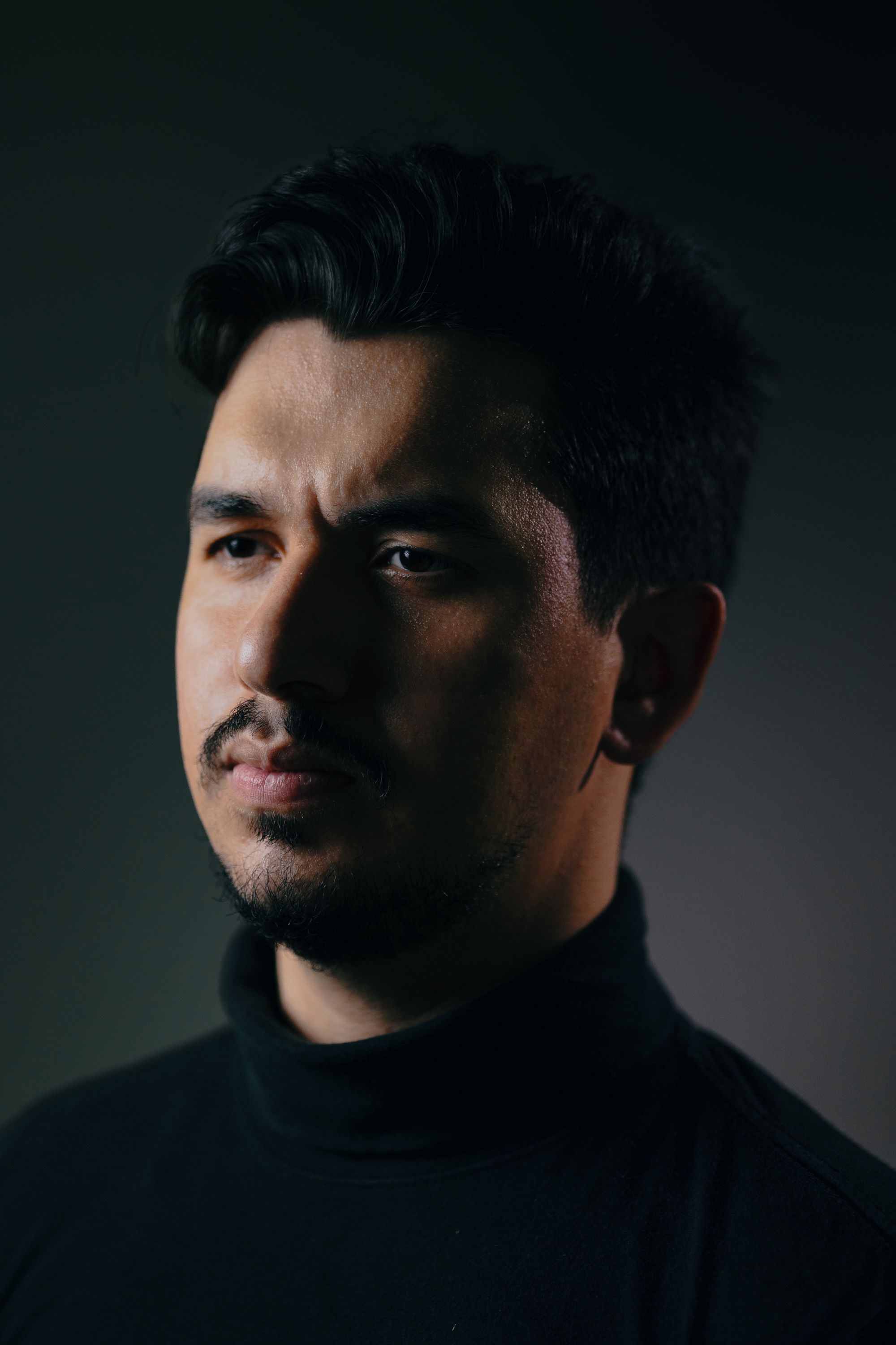 Cinematic close-up of a man in a black turtleneck with controlled directional lighting