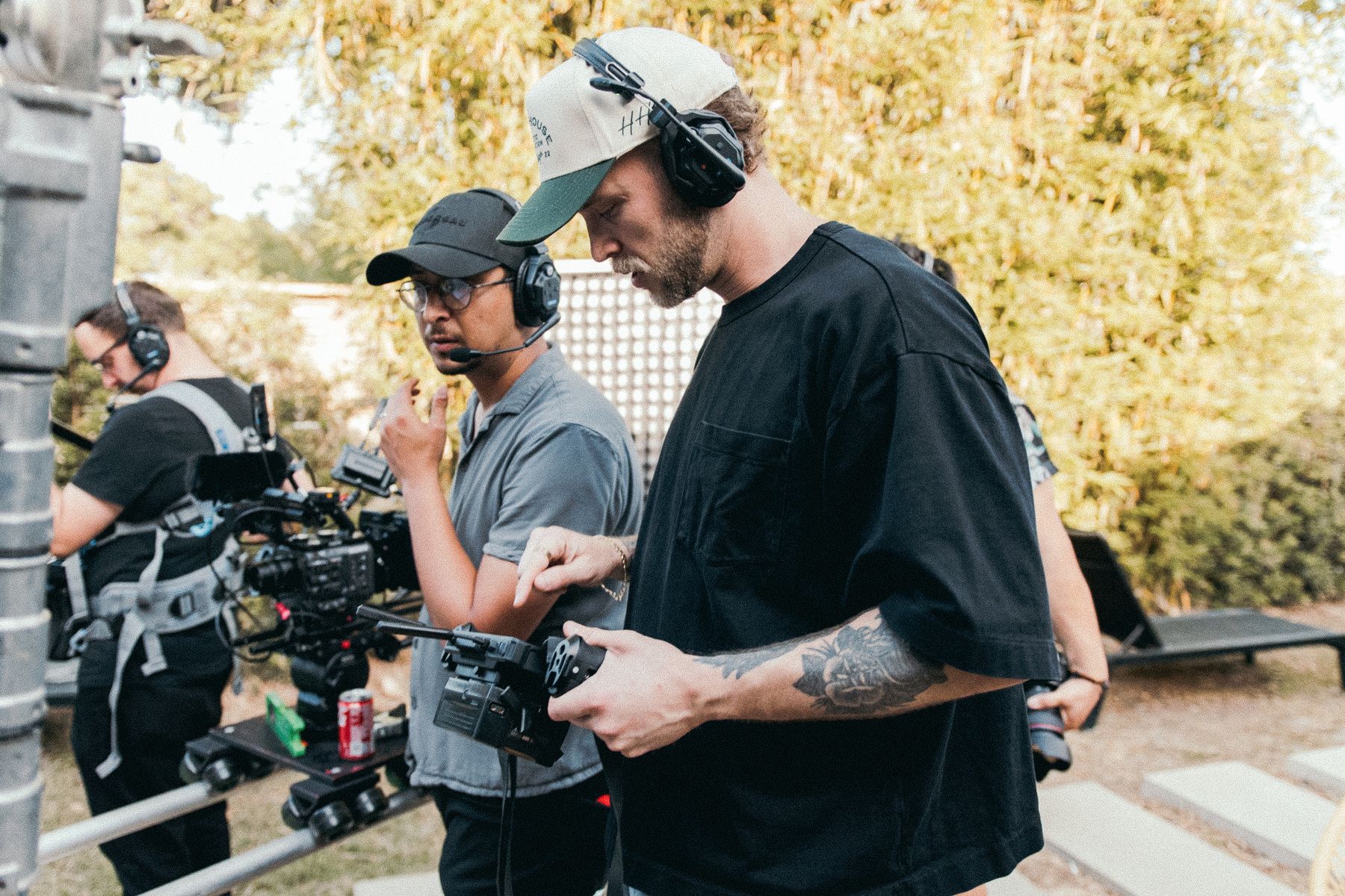 Film crew coordinating a location shoot with a cinema camera, headsets, and lighting equipment