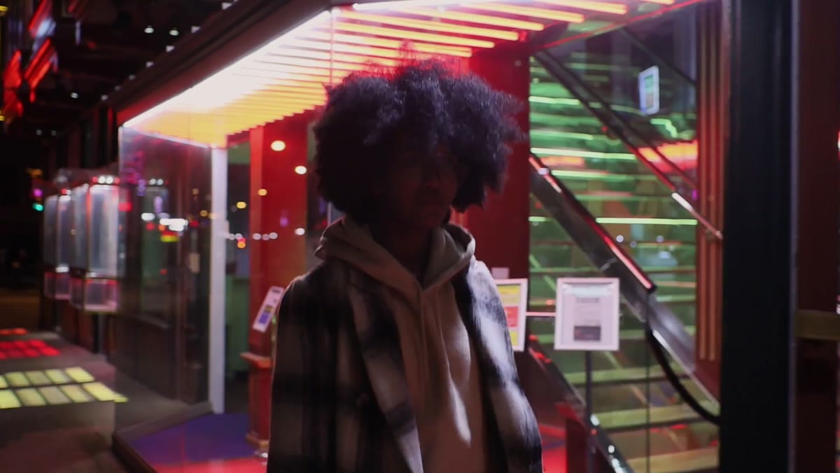 A woman walking along a neon-lit pathway at night