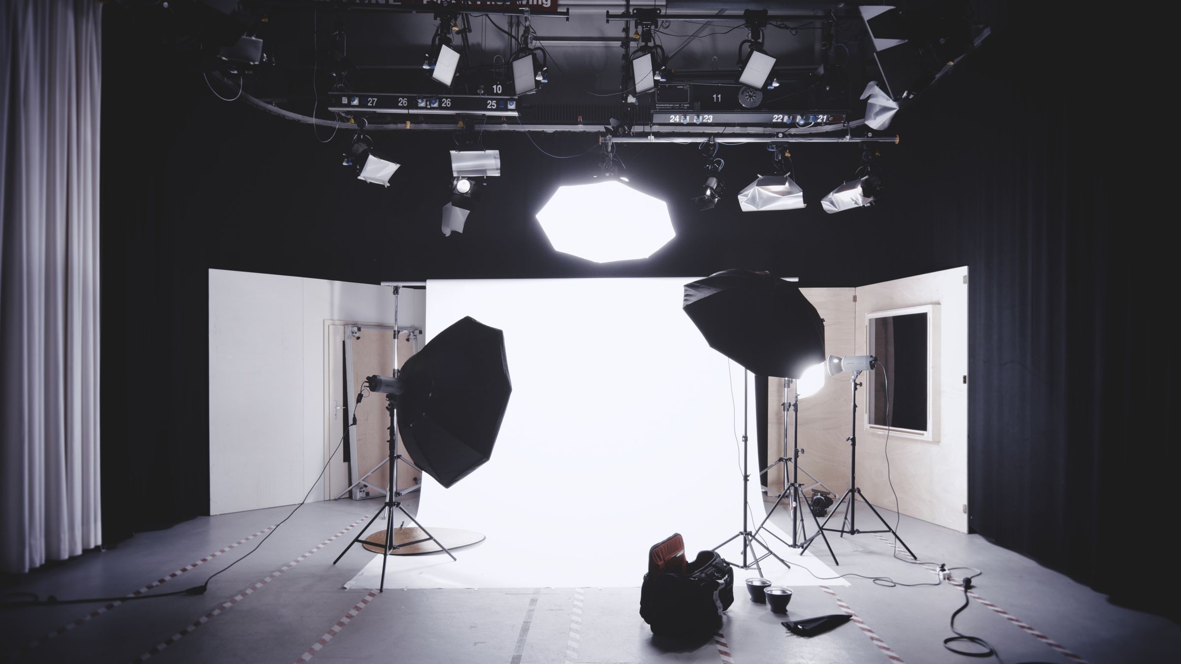 Professional photography studio with softbox lighting, overhead lights, and a white seamless backdrop